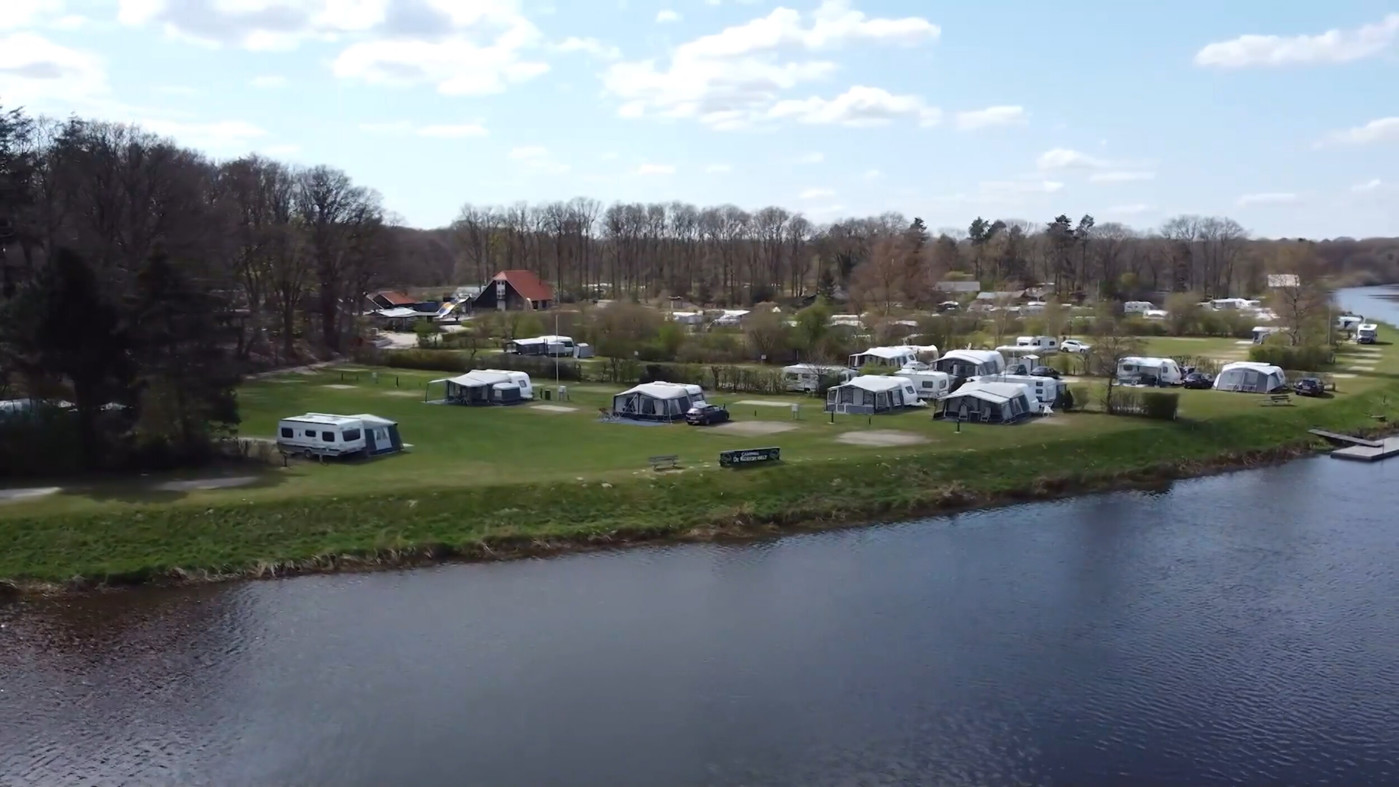 Vakantiepark aan het water met caravans en tenten