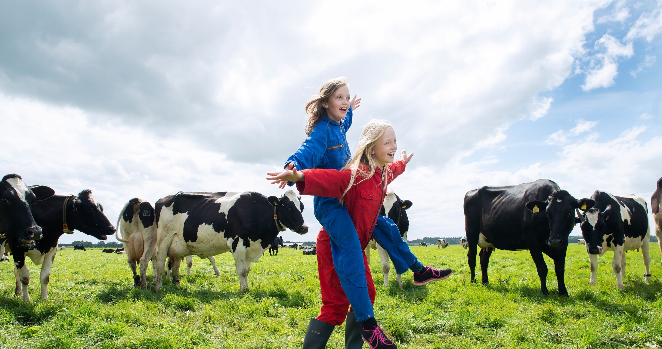 Twee kinderen in overalls in weiland tussen koeien