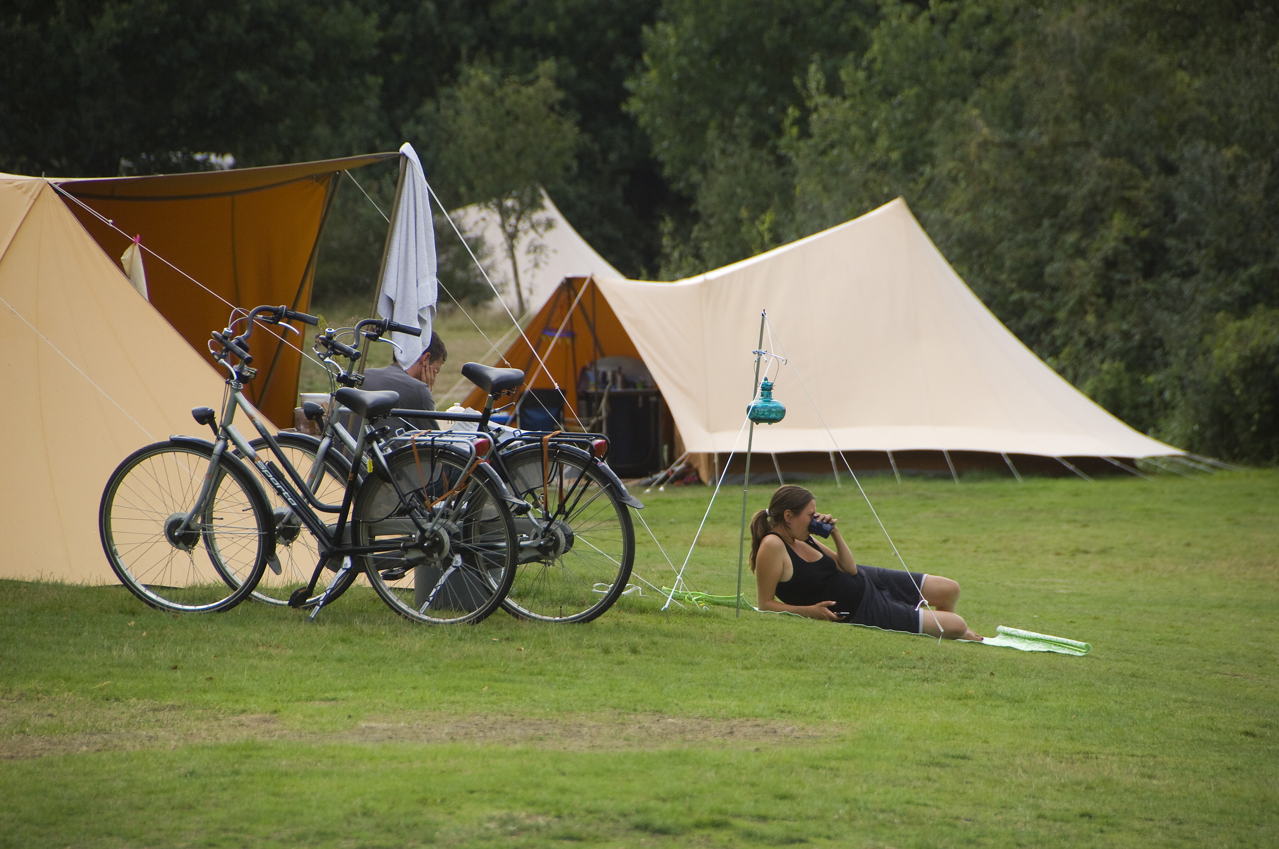 Iemand ligt naast een tent en fietsen op een groen veld