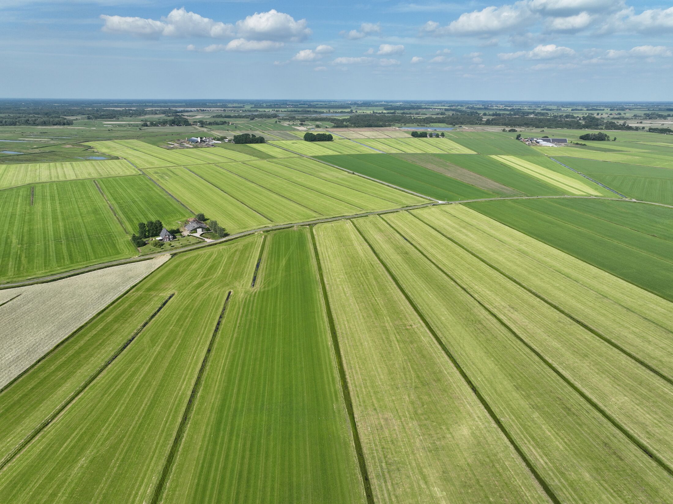 Vogelperspectief landschap vol met verschillende tintengroen kavels en af en toe een woning ertussen