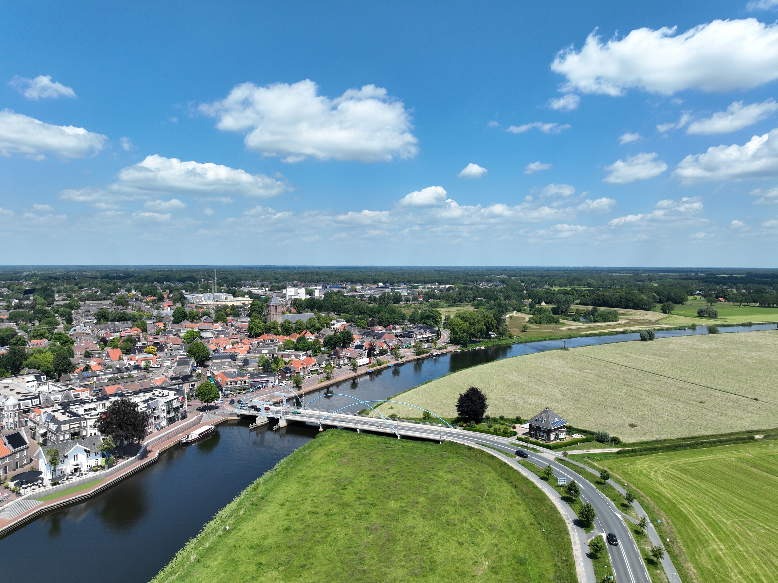 Een brug die over een brede rivier rijkt vanuit het landschap naar een stad