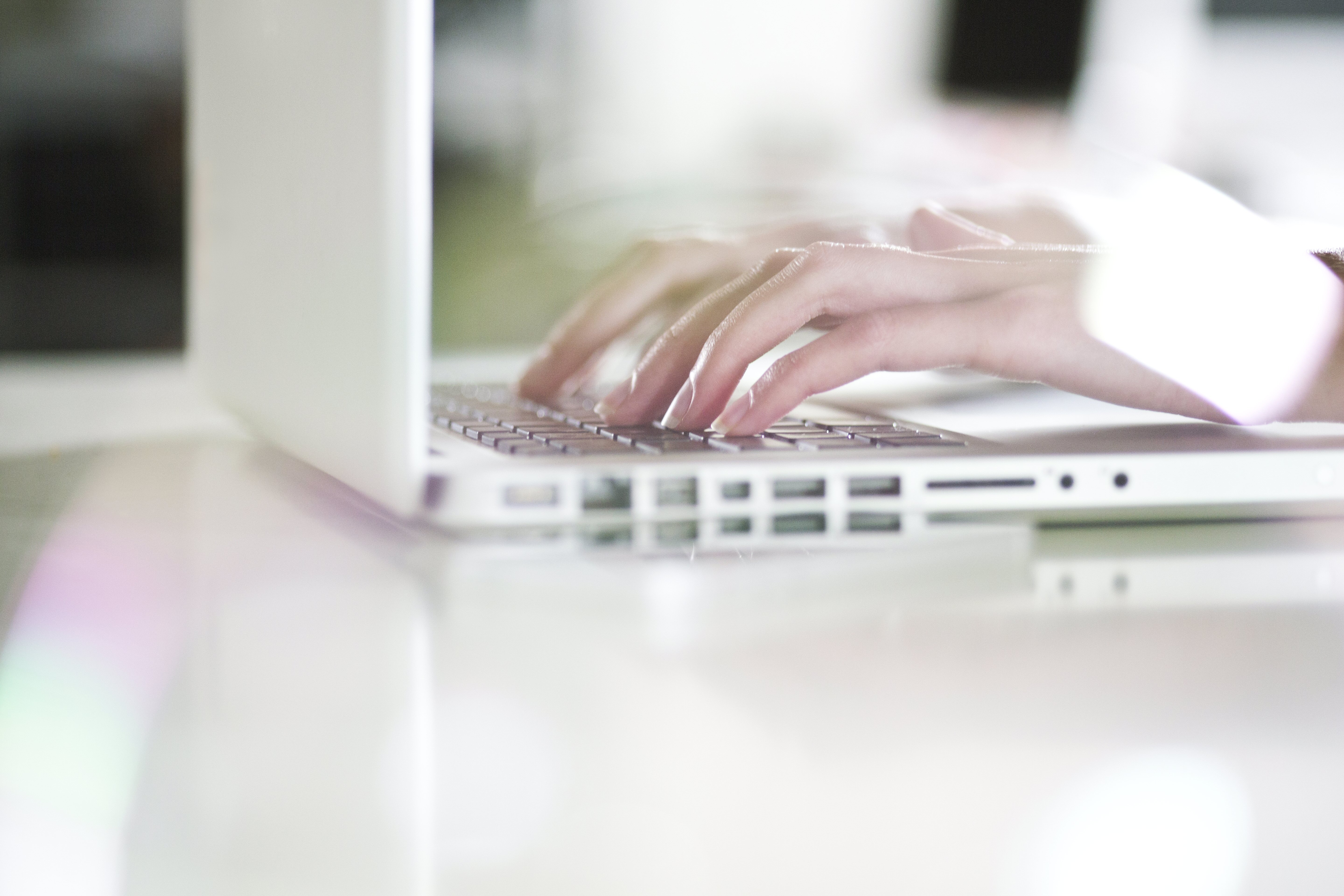 Handen die typen op witte laptop
