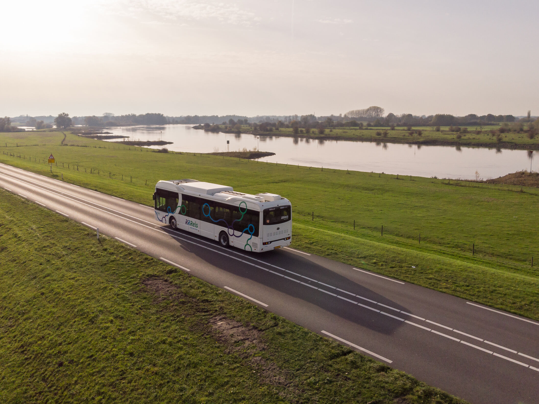 Bus op eenverkeersweg tussen weilanden