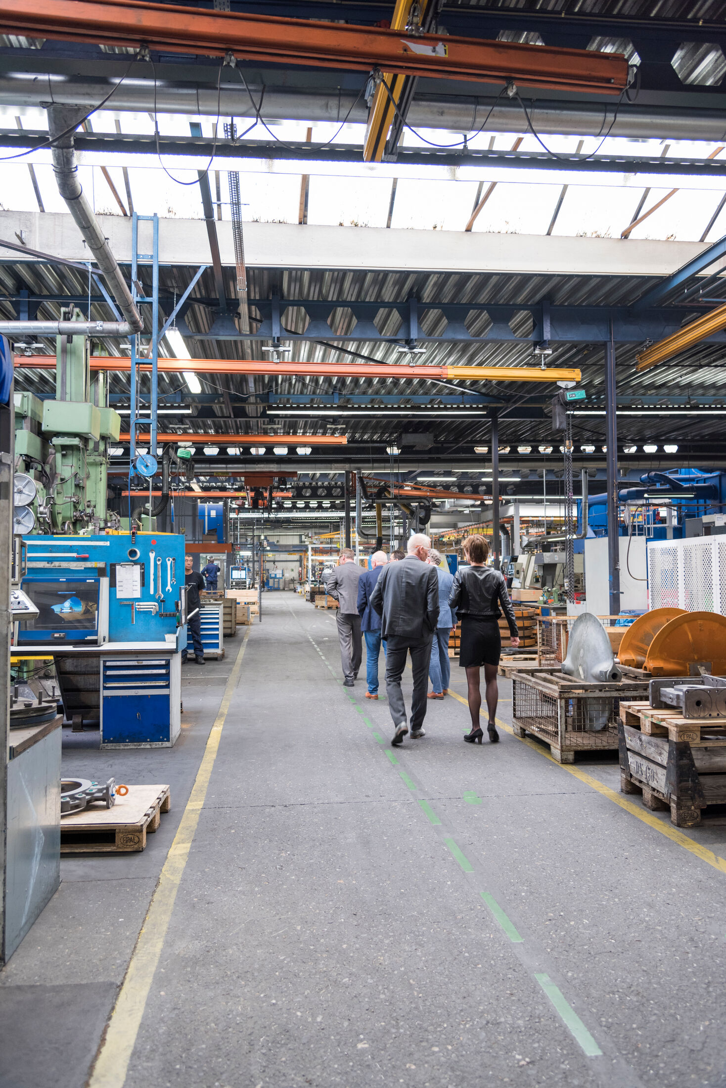Mensen lopen in groepje door indoor werkgebied met machines