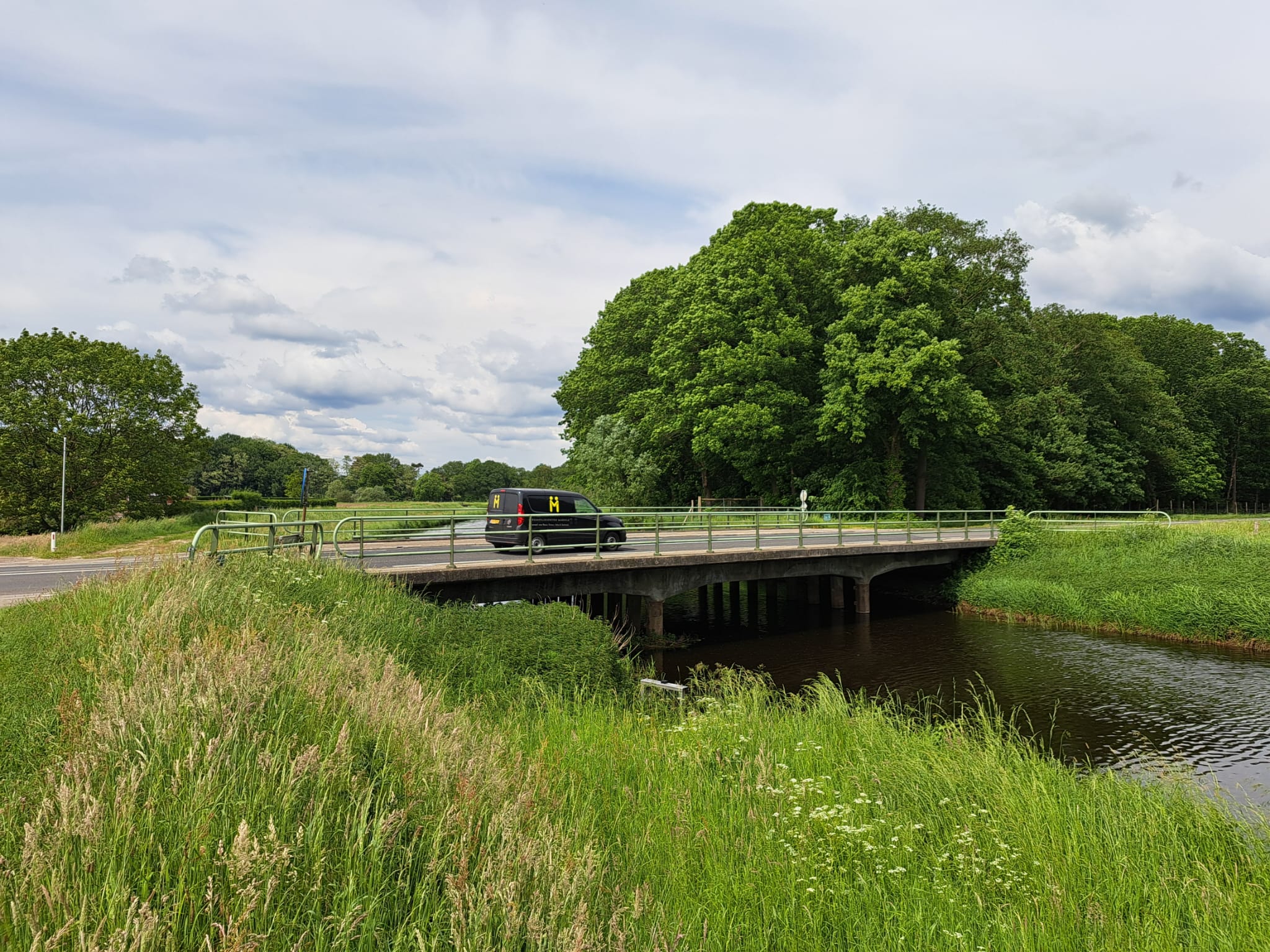 Auto die rijdt over bruggetje tussen groen landschap
